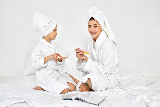mother and daughter holding nail file and making manicure - Fotoğraf, Görsel