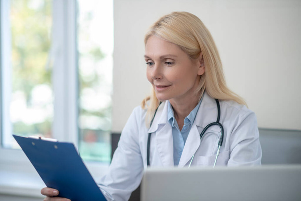 Attentive interested physician reading studying document - Photo, image