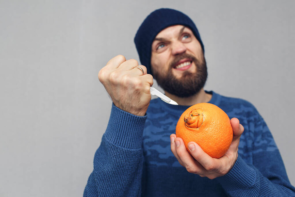 wściekły brodaty mężczyzna chce wyciąć pępk pomarańczy skalpelem. koncepcja problemów spowodowanych hemoroidami - Zdjęcie, obraz