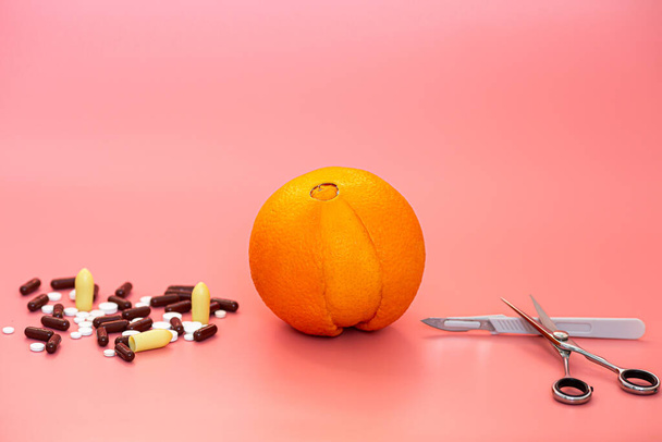 orange like a vagina, scalpel, scissors on a pink background. concept of prevention and treatment of gynecological diseases - Zdjęcie, obraz