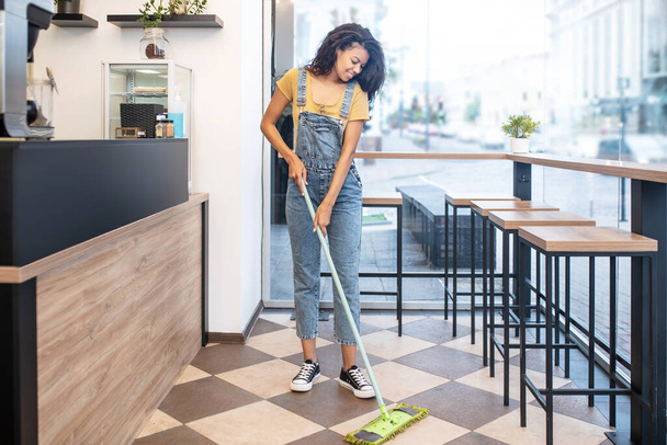 Young woman mopping floor in cafe - Foto, immagini