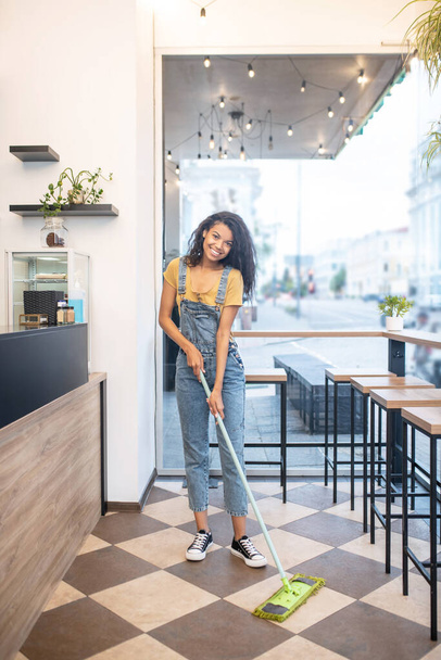 Young woman cleaning cafe in good mood - Fotoğraf, Görsel