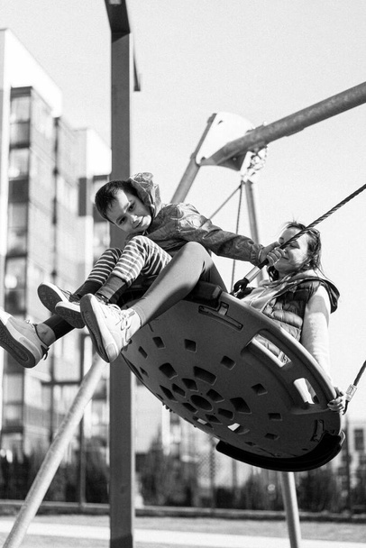 child boy plays on the street playground, rides on a swing. - Valokuva, kuva