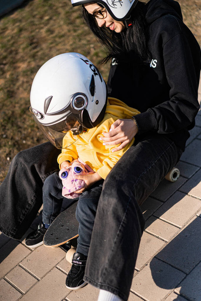 mom and child on a skateboard in helmets - Foto, Bild