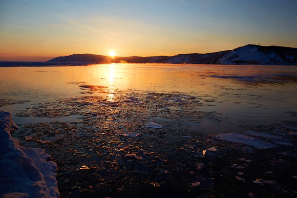 Beautiful sunset on Lake Baikal in spring. Melting ice and open water in the lake.  - Foto, Bild
