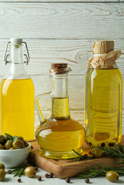Bottles of olive oil against white wooden background - Фото, изображение