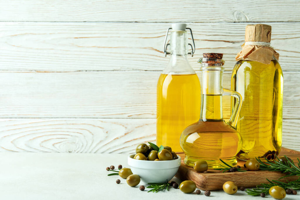 Flessen olijfolie tegen witte houten ondergrond - Foto, afbeelding