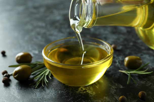 Olive oil pouring from bottle to bowl, close up - Фото, зображення