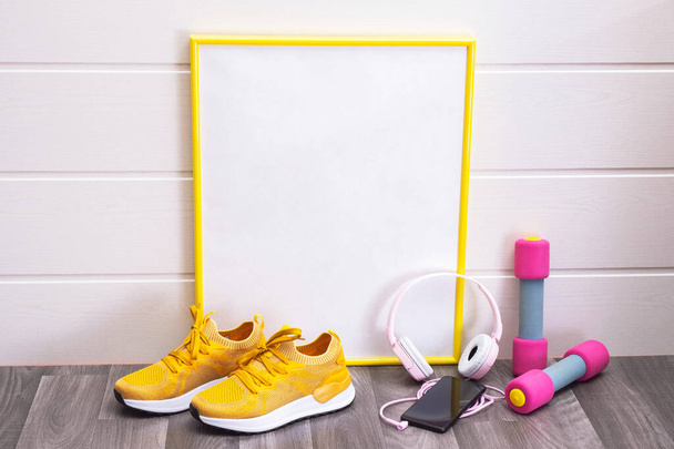 workout at home - dumbbells and yellow sneakers, a sign, with a yellow frame, for notes, headphones and a cell phone, all on a white background, close-up - Photo, image