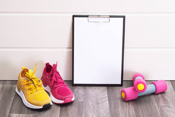 sports at home - pink and yellow sneakers, dumbbells and a note board close-up - Foto, Imagem