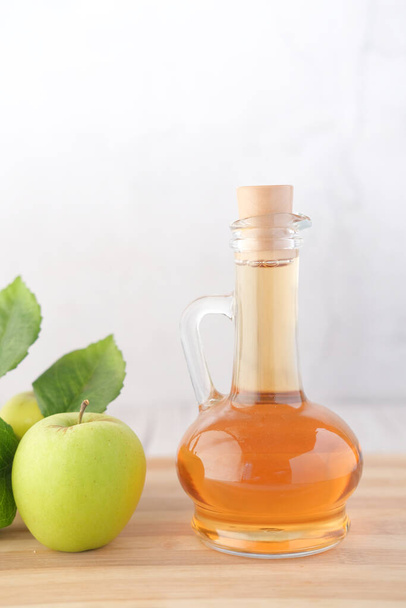 яблучний оцет у скляній пляшці зі свіжим зеленим яблуком на столі
  - Фото, зображення