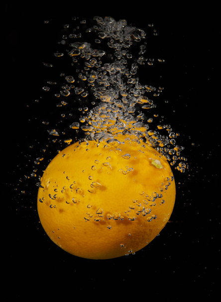Limão espirrando na água em um fundo preto - Foto, Imagem