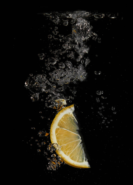 Lemon splashing in water on a black background - Foto, Bild