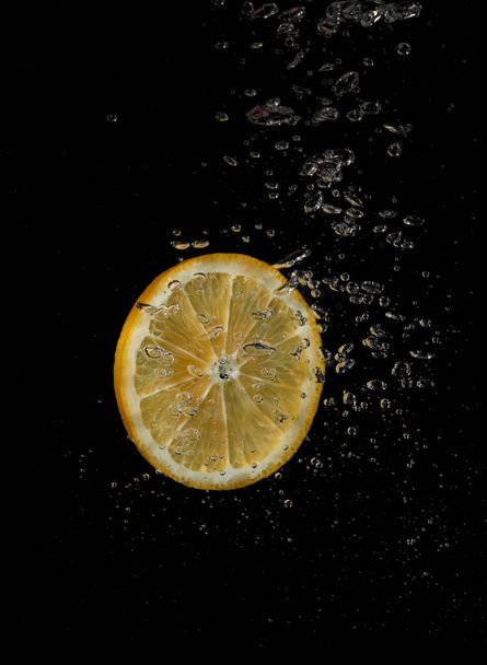 Lemon splashing in water on a black background - Foto, Imagen