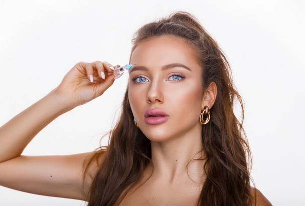 Attractive young woman gets cosmetic injection, isolated over white background. Doctors hands making an injection in face. Beauty Treatment. - Photo, Image