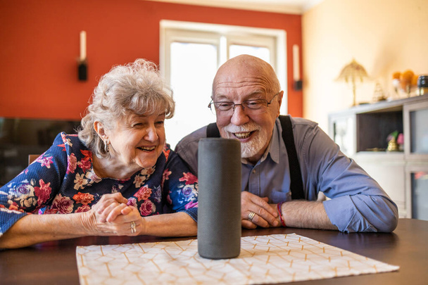 Восхитительная пожилая пара, использующая виртуального ассистента дома - Фото, изображение