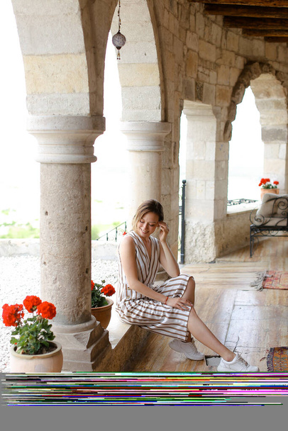 Caucasian girl sitting in arch of living room leaning on column. - Photo, Image