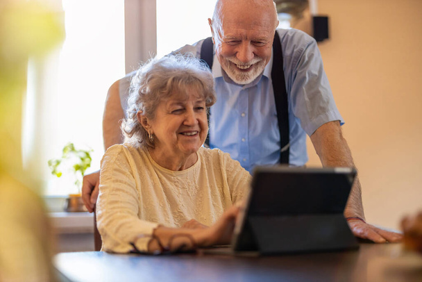 Счастливая пожилая пара с помощью цифрового планшета дома - Фото, изображение