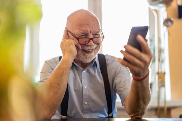 Shot of a senior man using a mobile phone at home - Foto, Bild