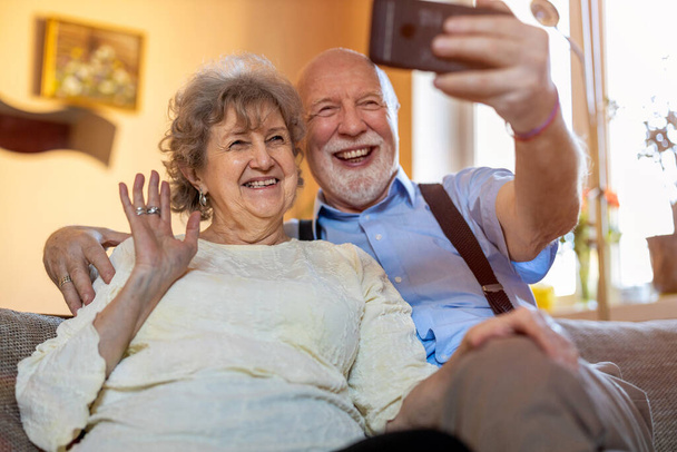 Heureux couple de personnes âgées utilisant un téléphone mobile pour un appel vidéo  - Photo, image