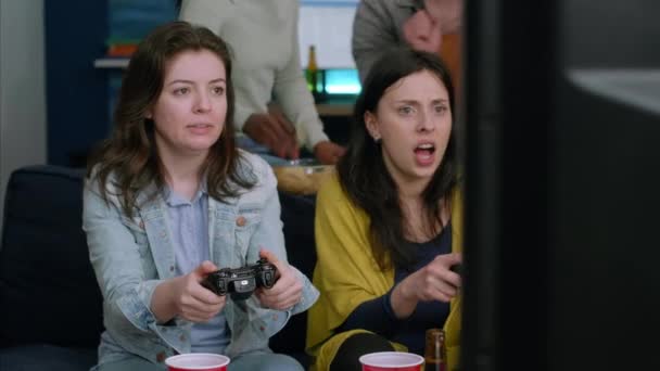 Front view of womens playing videogames μάχη στην τηλεόραση χρησιμοποιώντας ελεγκτή τυχερών παιχνιδιών - Πλάνα, βίντεο
