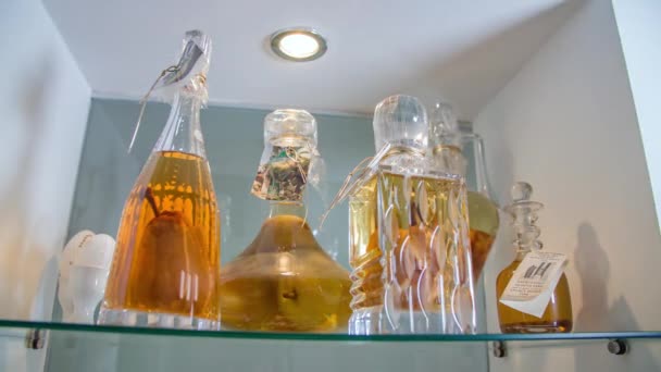 Belle bottiglie di vetro con liquore sullo scaffale del negozio - Filmati, video
