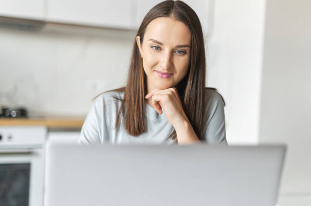 Charming young woman using laptop computer for working from home - Foto, Bild
