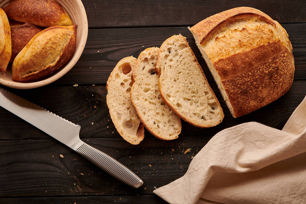 Świeżo upieczony domowy tartinowy chleb na ciemnym drewnianym stole - Zdjęcie, obraz