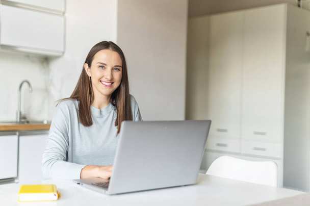 Charming young woman using laptop computer for working from home, - Foto, afbeelding