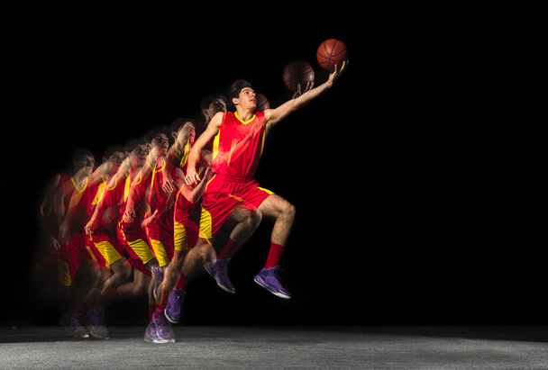 Young caucasian basketball player in motion and action in mixed light on dark background. Concept of healthy lifestyle, professional sport, hobby. - Fotoğraf, Görsel