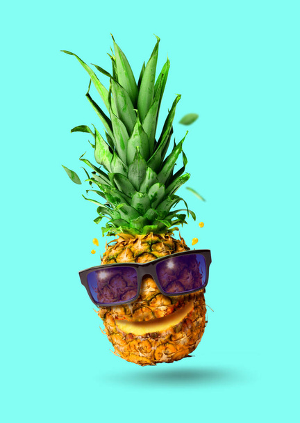 Забавный тропический прыжки ананас фрукты с солнцезащитными очками, праздничная концепция, изолированные на бирюзовом фоне - Фото, изображение