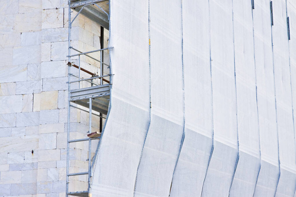 Metal scaffolding on a construction site built with prefabricated components to work safely on the facade of a building for the renovation of the plaster wall or realization of thermal insulation to improve the energy efficiency of the building. - Photo, Image