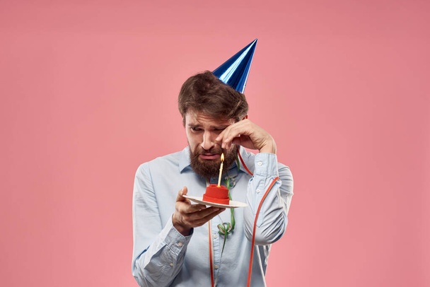 Syntymäpäivä mies, jolla on kakku ja kynttilä vaaleanpunaisella taustalla - Valokuva, kuva