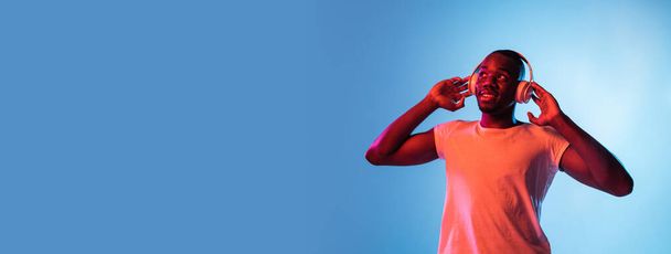 Een jonge Afrikaanse man geïsoleerd op gradiënt achtergrond in neon licht - Foto, afbeelding
