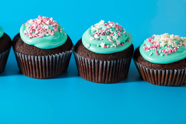 Cupcakes with turquoise icing and sugar sprinkles in the form of pink hearts and stars. Sweets for birthday, Valentine's day, children's holiday, Easter. Side view - Photo, Image