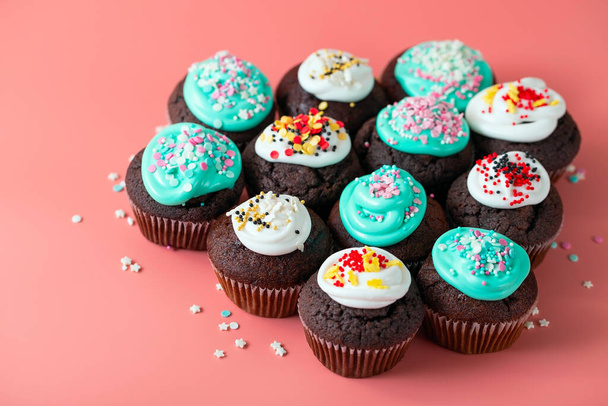 Chocolate cupcakes with turquoise and white icing and sugar shaped sprinkles. Sweet holiday food close-up on pink background - Foto, immagini