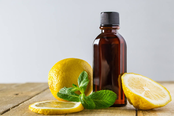 Aromatic oil with lemon and mint on a wooden background. Product for relaxation and spa therapy. - Фото, зображення