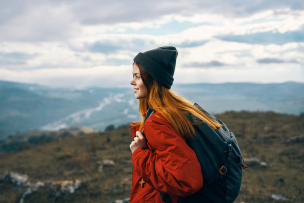 mujer viaja en las montañas paisaje mochila chaqueta roja y sombrero modelo - Foto, imagen