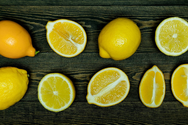Limoni interi e mezze limoni su fondo di legno scuro - Foto, immagini
