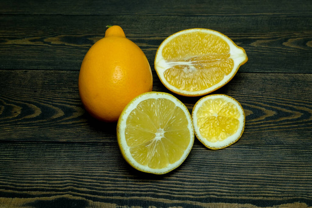 Hele citroenen en halve citroenen op een donkere houten ondergrond - Foto, afbeelding