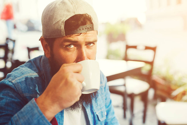 Hipster bearded man drinks coffee on outdoors terrase. People, lifestyle cocnept. Urban street style. Coffee break time. - Photo, Image