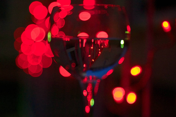 A closeup shot of a wine glass with colorful lights in the background - Foto, afbeelding