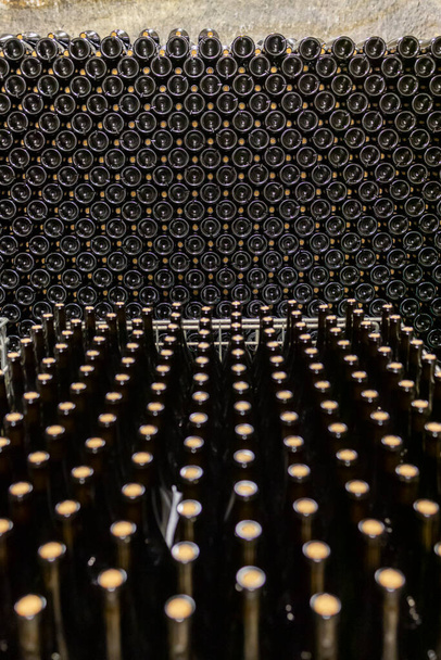 large number of wine bottles stacked in background - Photo, Image