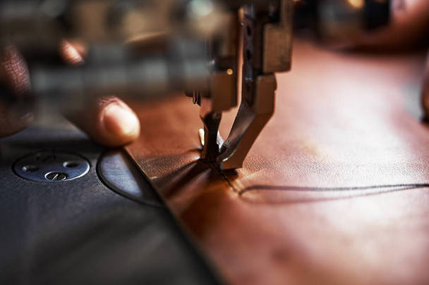 Proceso de trabajo del artesano del cuero. Tanner o skinner cose el cuero en una máquina de coser especial, cerca de costura up.worker en la máquina de coser - Foto, imagen