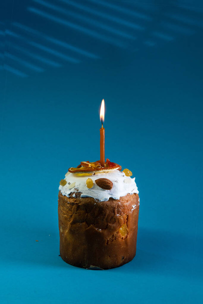 Traditional Easter cake on blue background. Migdal, candied fruits, raisins, decor colorful eggs, candles are burning. Orthodox treat. Copy space. Vertical photo - Φωτογραφία, εικόνα