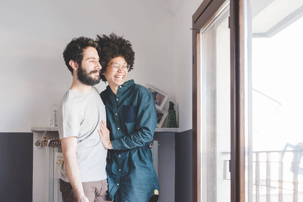 Joven pareja multiétnica abrazándose sonriendo en el interior - Foto, imagen