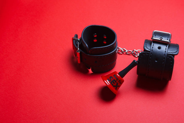 BDSM handcuffs and bell for sex on red background - Photo, Image