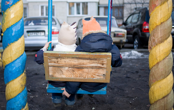 La ville sur l'aire de jeux et deux enfants sur une balançoire
 - Photo, image