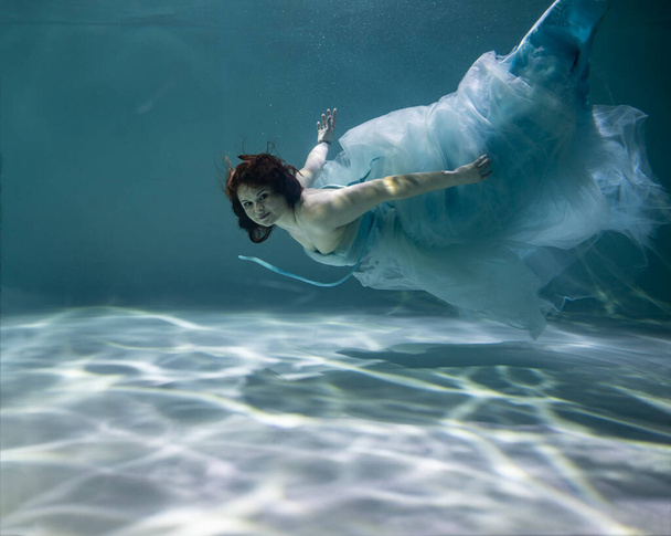 Mavi ve beyaz fayanslar içinde güzel bir kız mavi arka planda suyun altında - Fotoğraf, Görsel