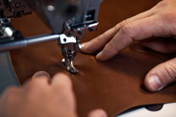 Processus de travail de l'artisan du cuir. Tanner ou skinner coud du cuir sur une machine à coudre spéciale, close up. Travailleur couture sur la machine à coudre - Photo, image